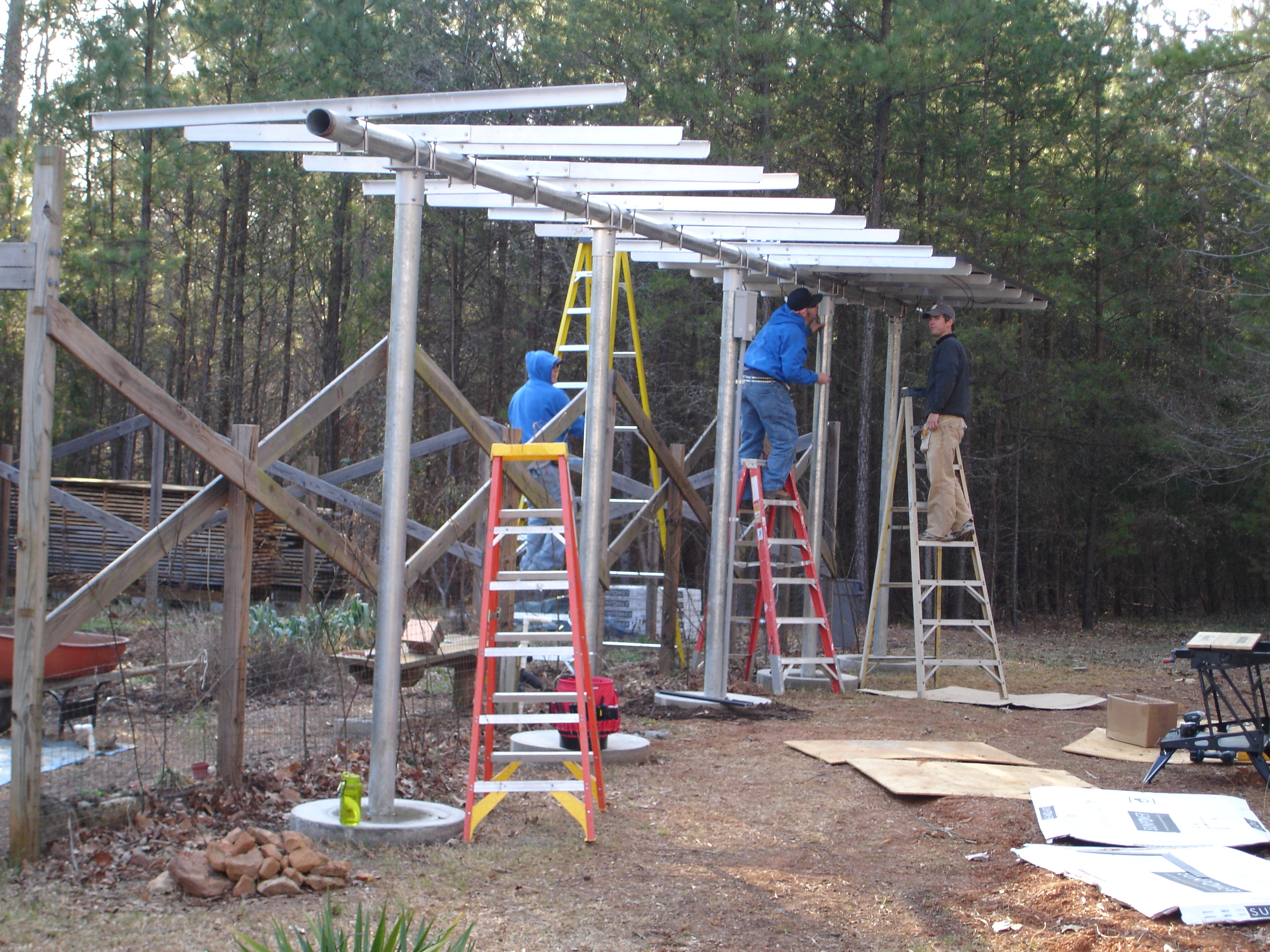 An installation view showing the vertical poles set in concrete and the mounting structure for the solar panels being readied.